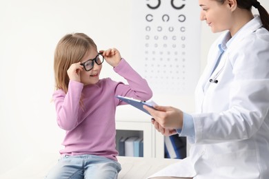 Vision testing. Little girl trying glasses at ophthalmologist office