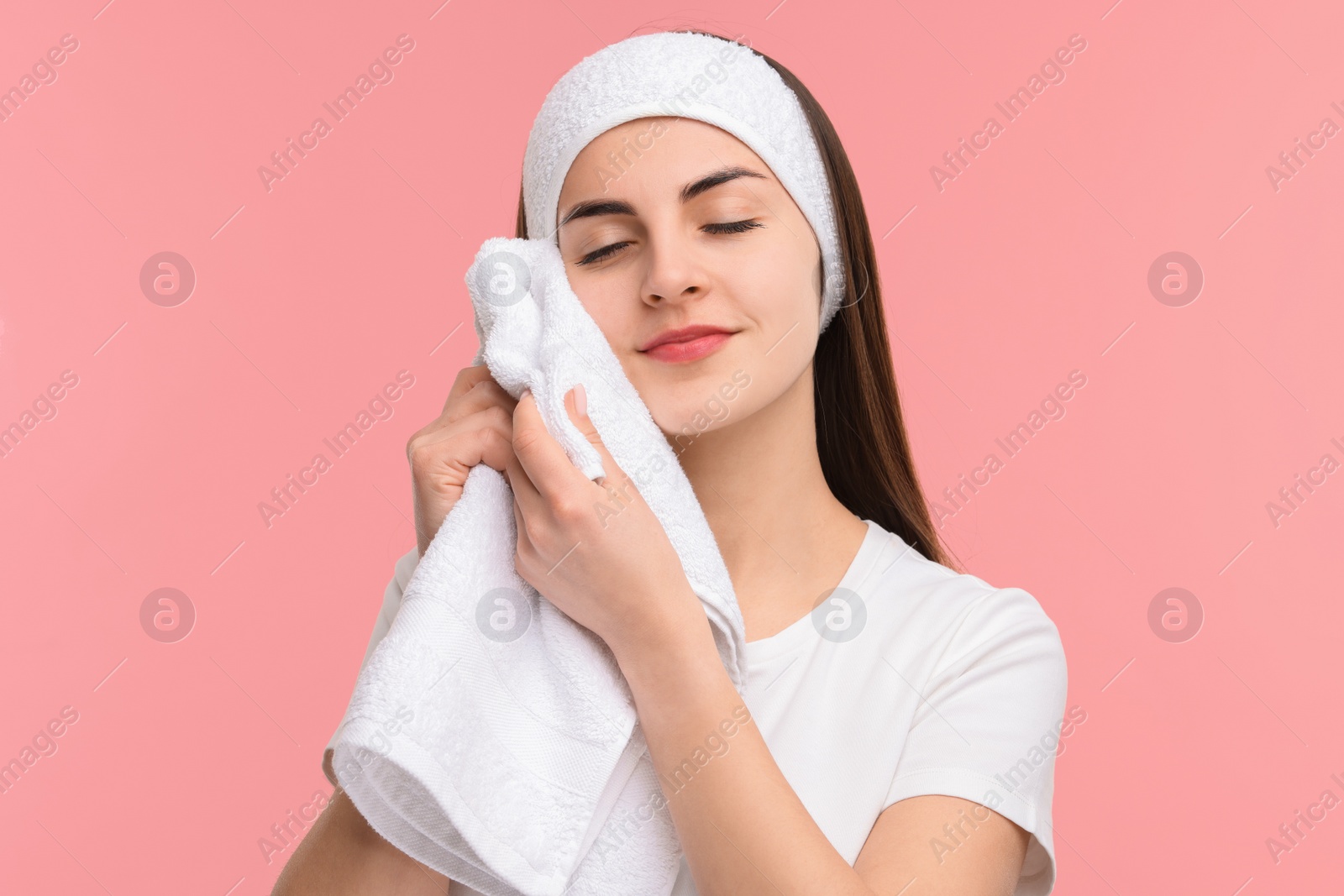 Photo of Washing face. Young woman with headband and towel on pink background