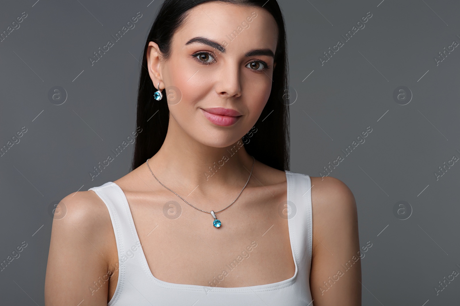 Photo of Beautiful young woman with elegant jewelry on dark grey background