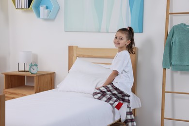 Photo of Cute girl changing bed linens in children room