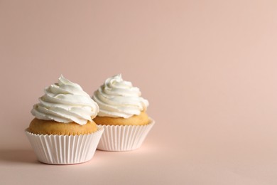 Delicious cupcakes with white cream on pink background. Space for text