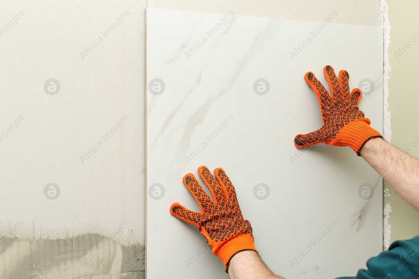 Photo of Man installing ceramic tile on wall, space for text. Building and renovation works