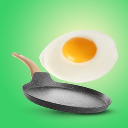 Image of Tasty fried chicken egg falling into frying pan on color background