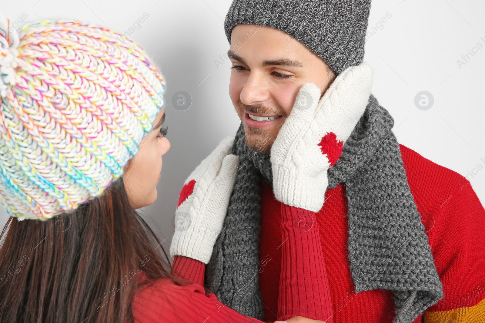 Photo of Young happy couple in warm clothes on light background. Christmas celebration