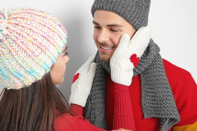 Young happy couple in warm clothes on light background. Christmas celebration