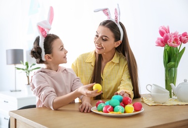 Photo of Mother and daughter with bunny ears headbands and painted Easter eggs at home