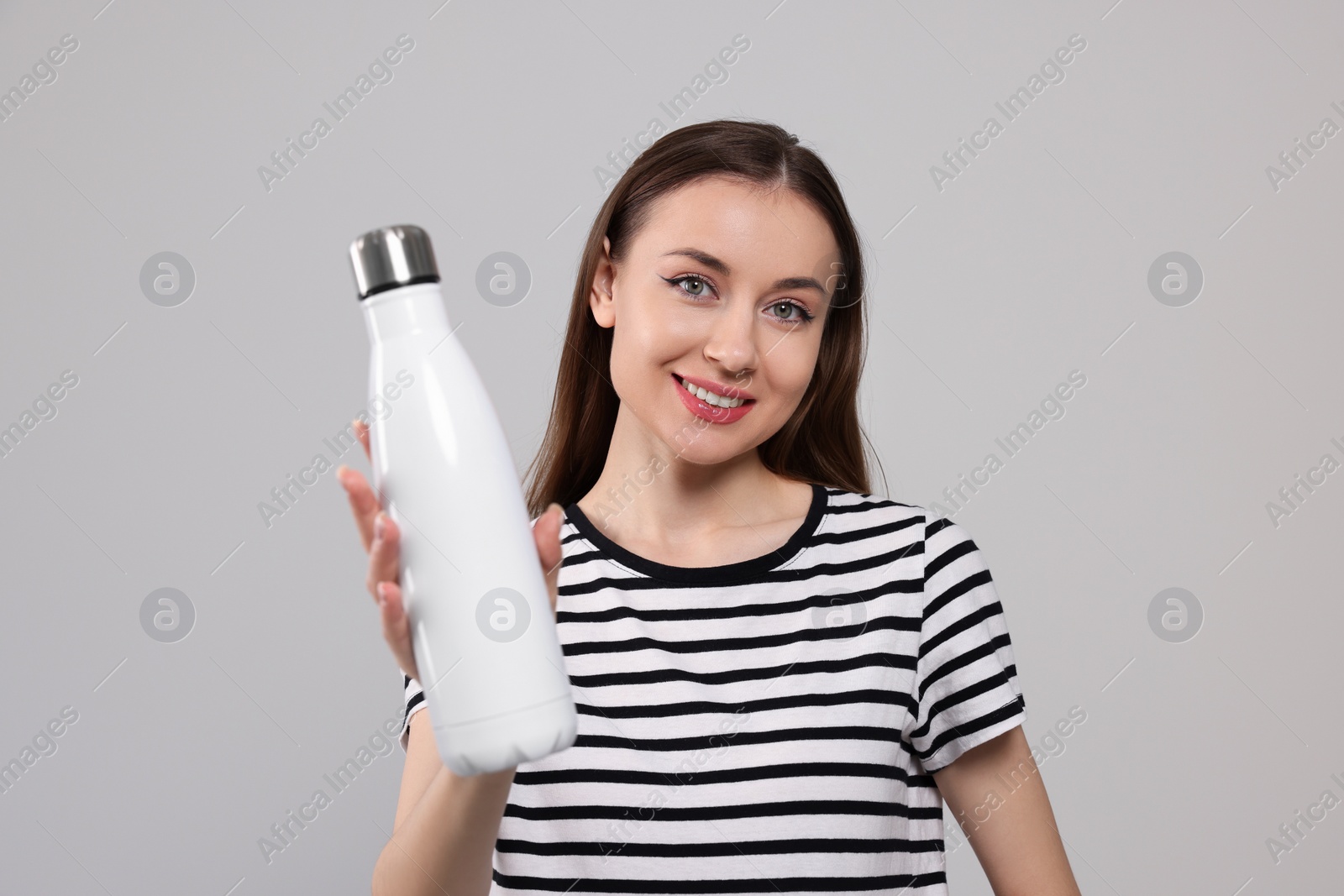 Photo of Beautiful young woman with thermos bottle on light grey background
