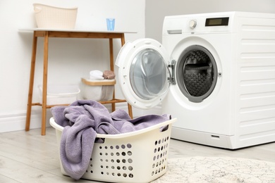 Photo of Basket with laundry and washing machine indoors
