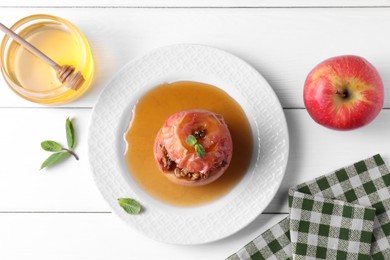 Photo of Tasty baked apple with nuts, honey and mint on white wooden table, flat lay