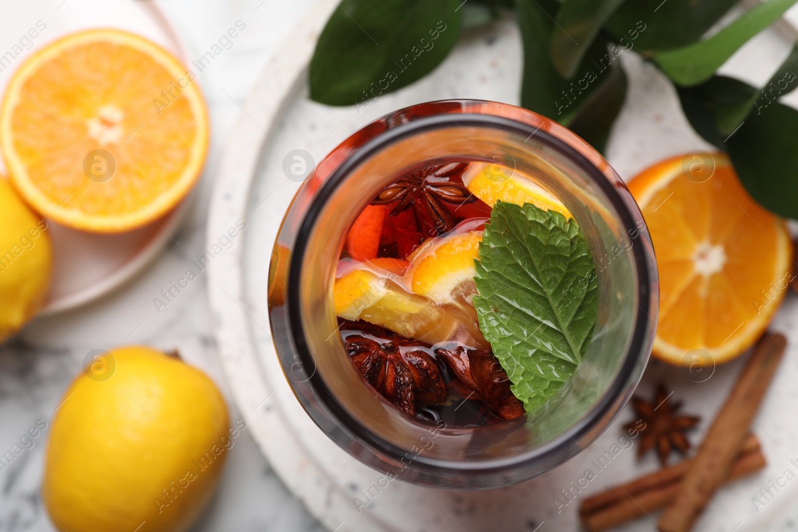 Photo of Delicious punch drink, spices and citrus fruits on white marble table, flat lay