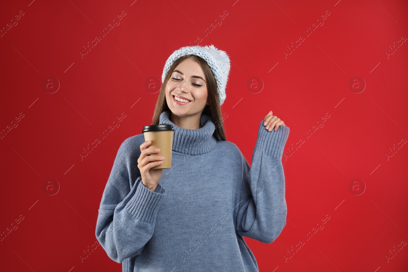 Photo of Happy beautiful woman with paper cup of mulled wine on red background