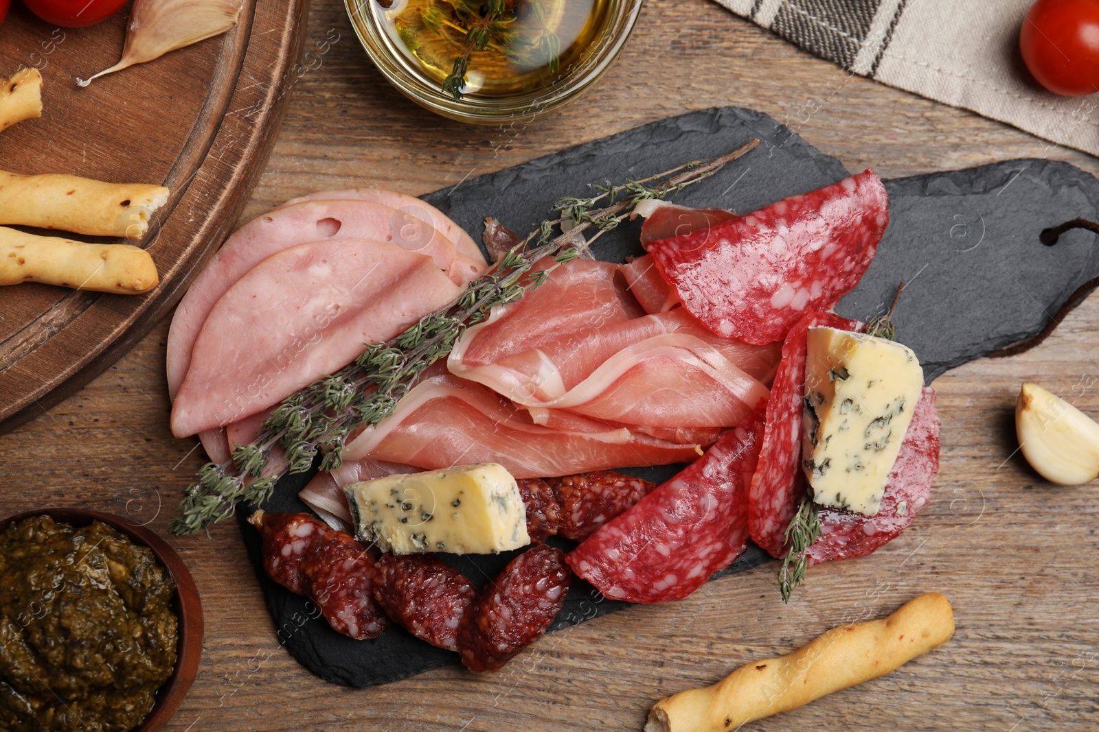 Photo of Tasty ham with other delicacies served on wooden table, flat lay