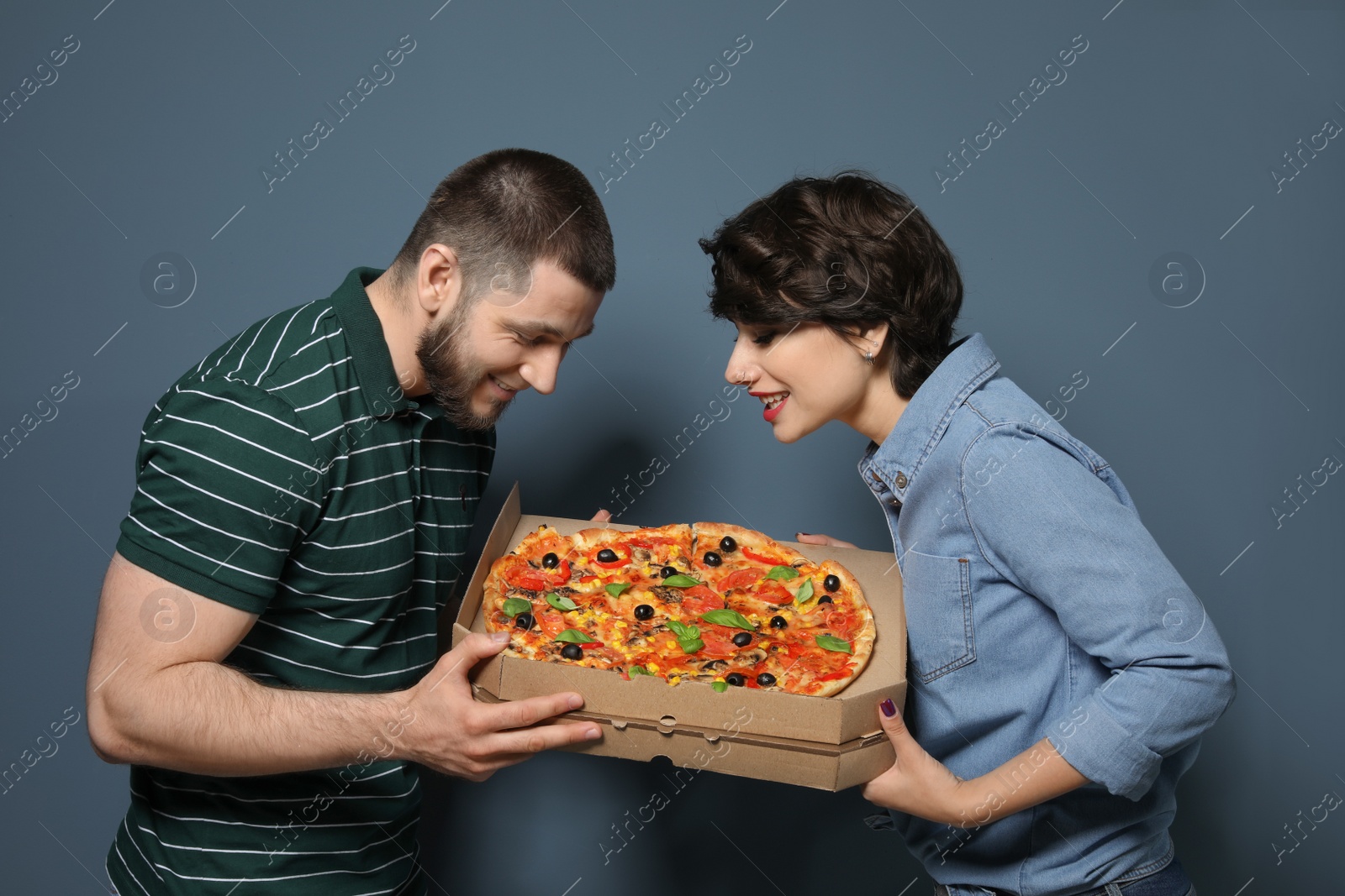 Photo of Attractive young couple with delicious pizza on color background