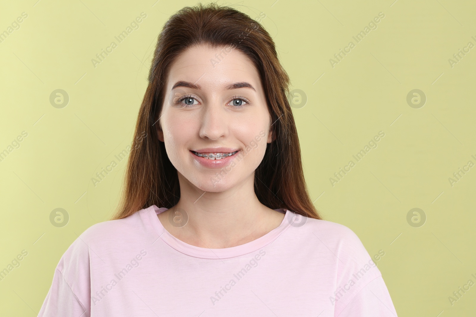 Photo of Portrait of smiling woman with dental braces on light green background