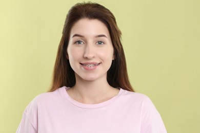 Portrait of smiling woman with dental braces on light green background
