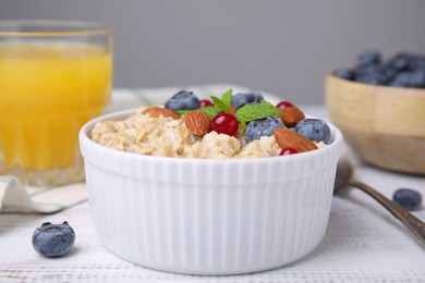 Oatmeal served with berries. almonds and mint on white table, closeup