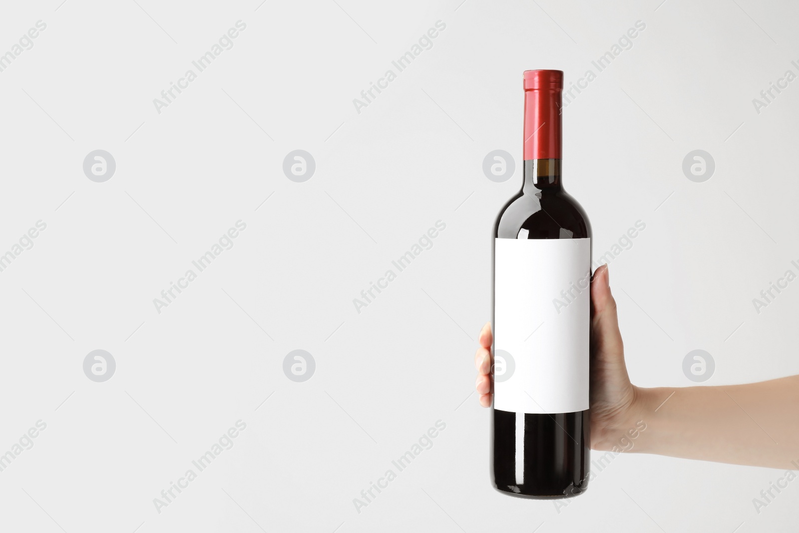Photo of Woman holding bottle with delicious wine on white background