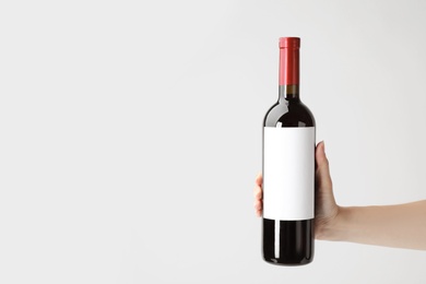 Woman holding bottle with delicious wine on white background