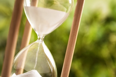 Photo of Hourglass with flowing sand on blurred background, closeup. Time management