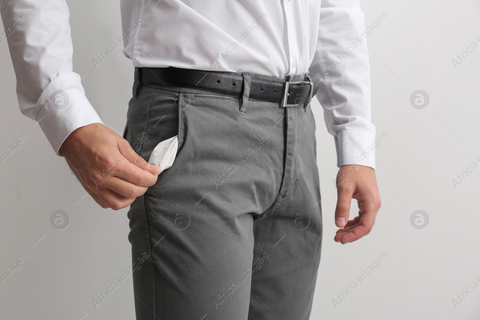 Photo of Businessman showing empty pocket on light background, closeup