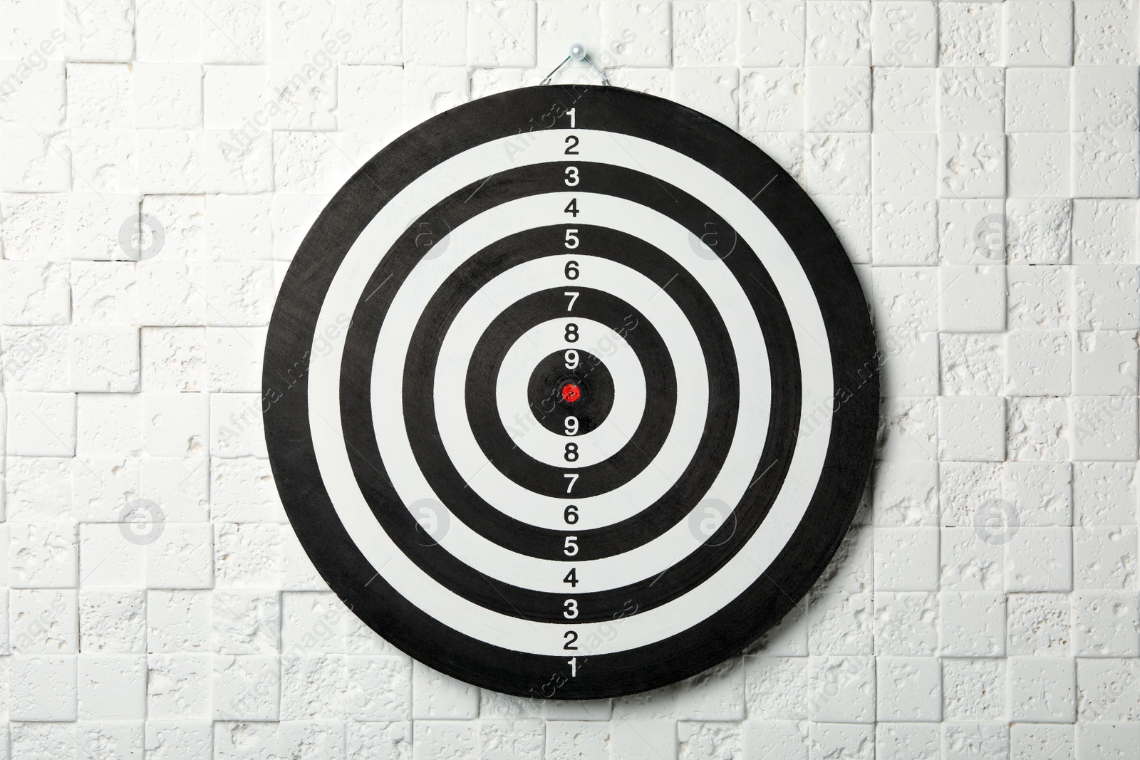 Photo of Dart board hanging on white textured wall