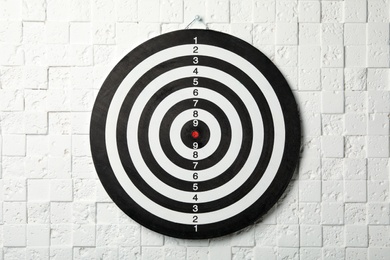 Dart board hanging on white textured wall