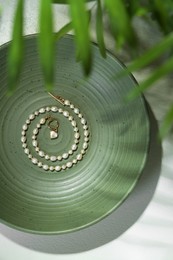 Photo of Elegant pearl necklace on white table, top view