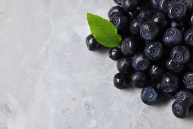 Ripe bilberries and leaf on grey marble table, closeup. Space for text