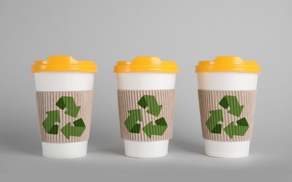 Image of Carton cups with recycling symbols on grey background