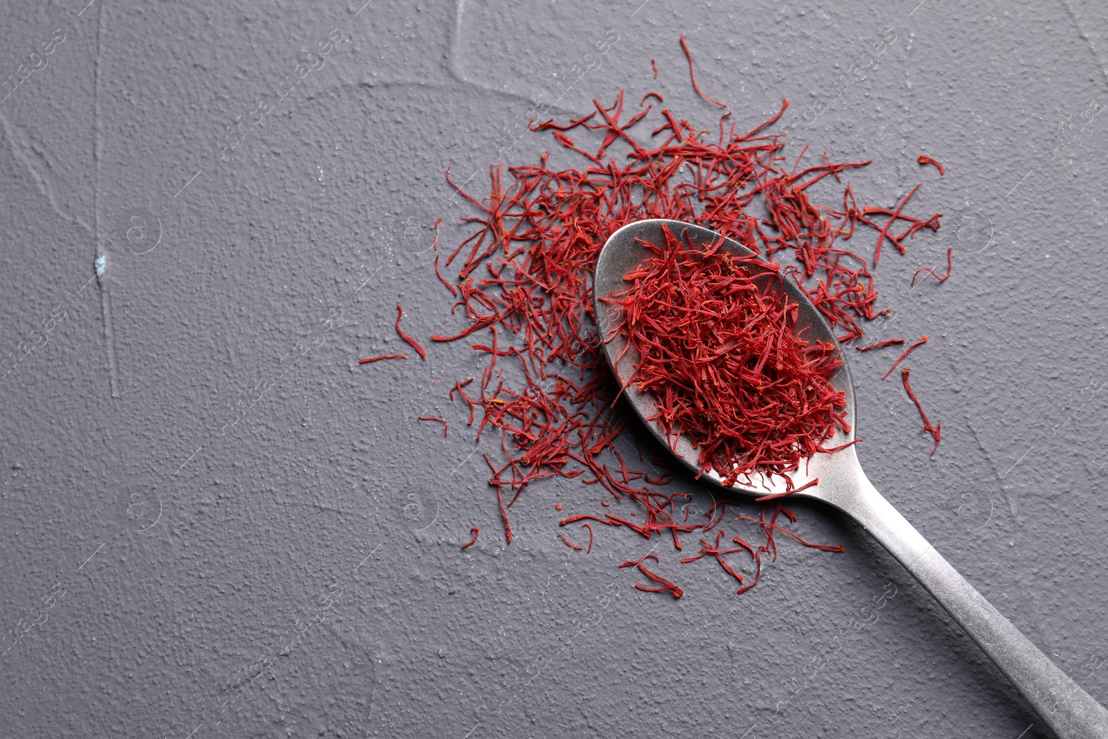 Photo of Aromatic saffron and spoon on gray table, top view. Space for text