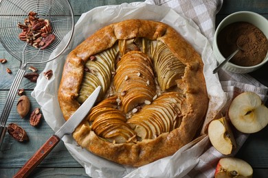 Delicious apple galette with pecans and cinnamon on wooden table, flat lay