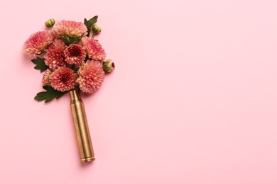 Photo of Beautiful flowers in bullet case on pink background, top view. Space for text