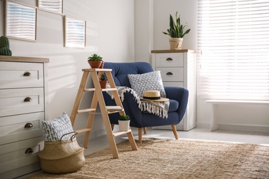 Photo of Stylish living room interior with wooden ladder and comfortable armchair