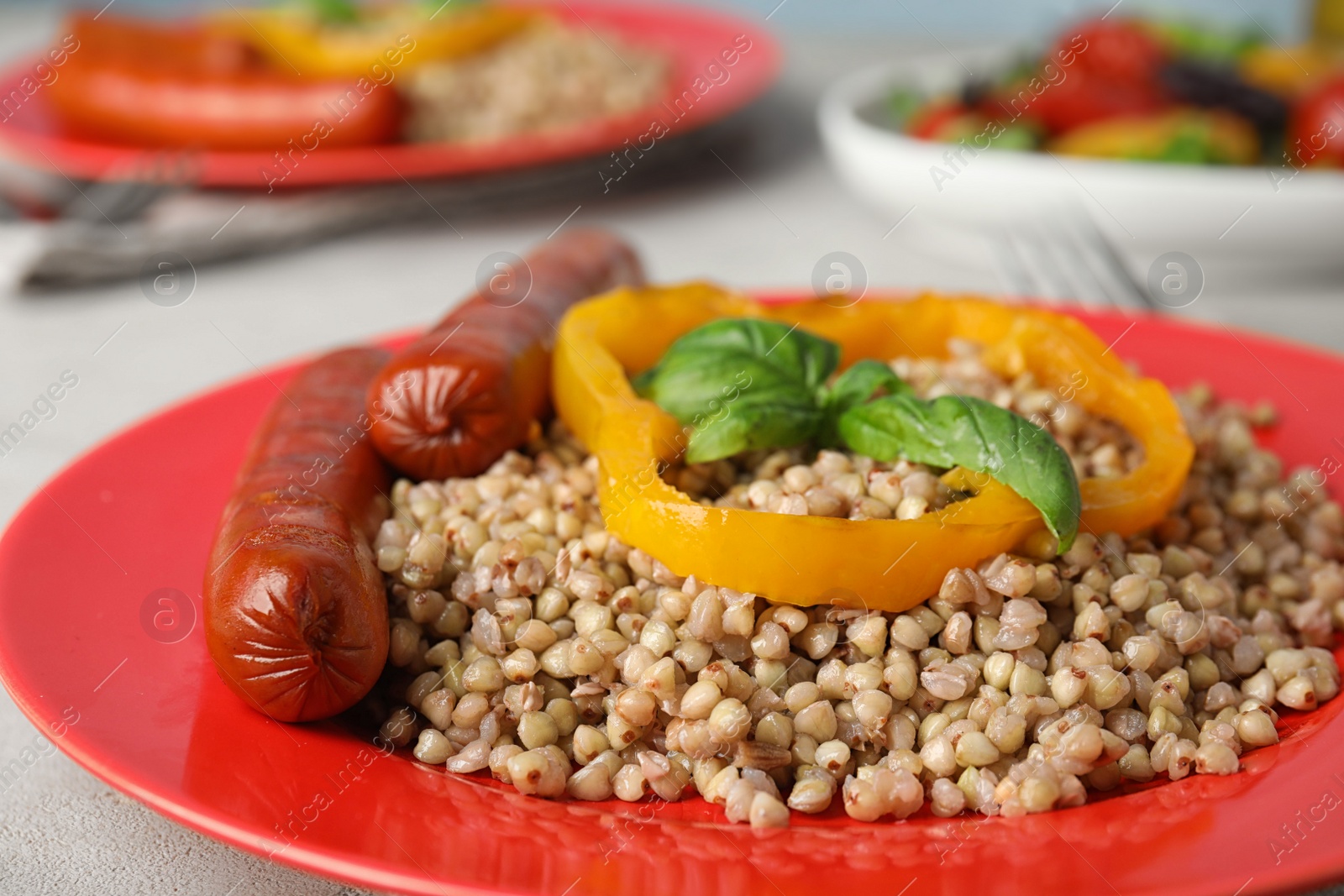 Photo of Tasty buckwheat porridge with sausages on plate, closeup