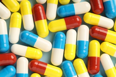 Many antibiotic pills on light blue background, top view