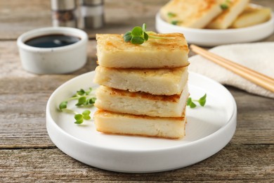 Photo of Delicious turnip cake with microgreens served on wooden table