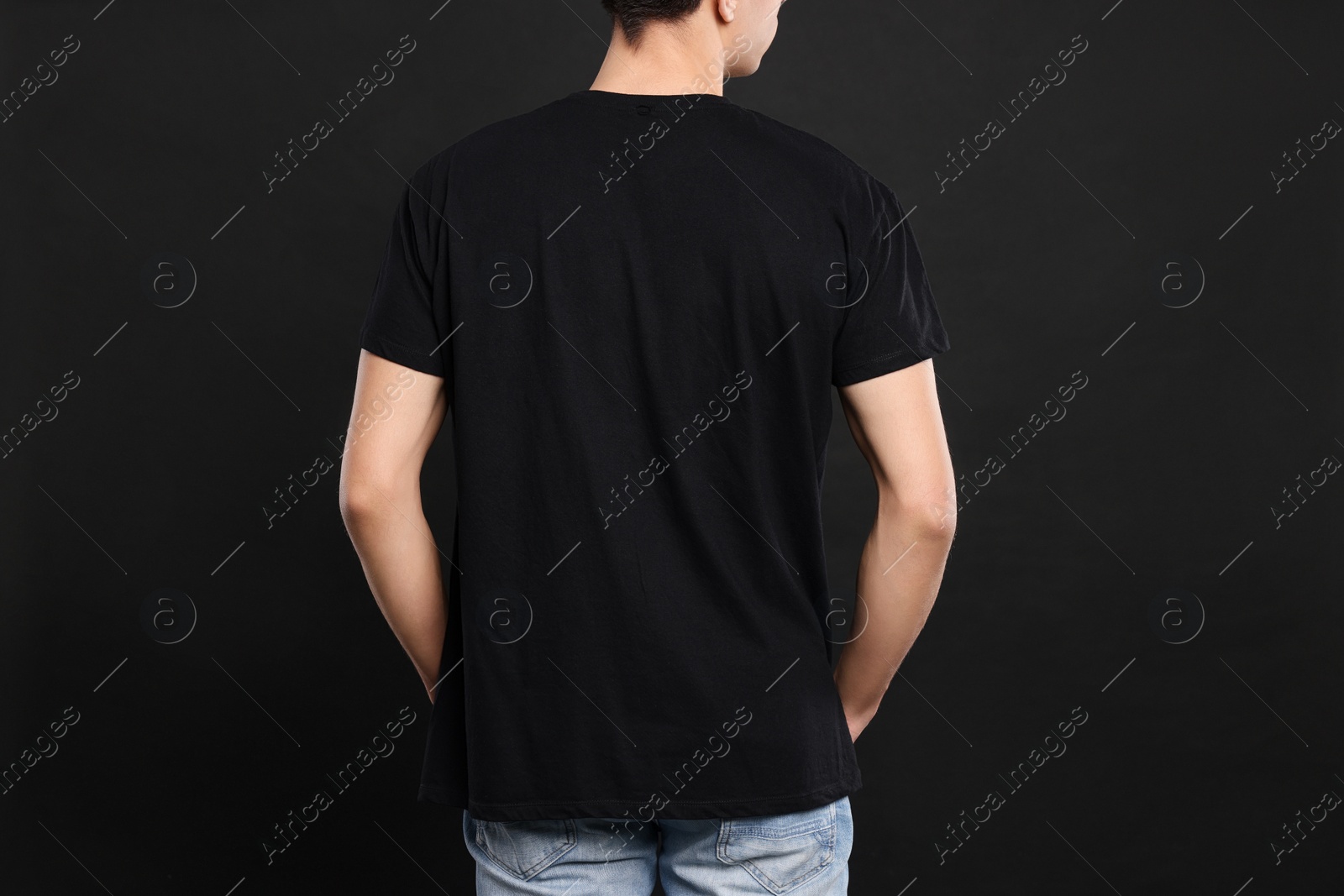 Photo of Man wearing stylish t-shirt on black background, back view. Mockup for design