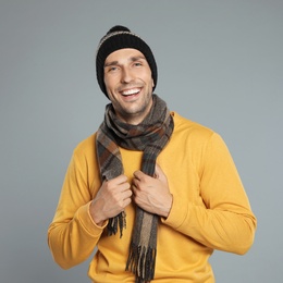 Photo of Happy young man in warm clothes on grey background. Winter season
