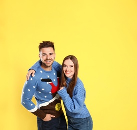 Photo of Couple wearing Christmas sweaters on yellow background