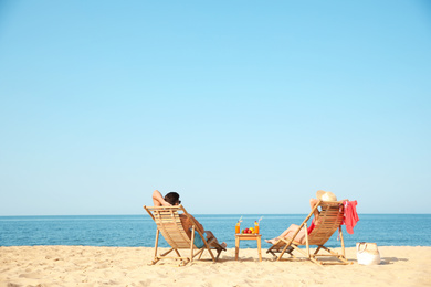 Photo of Couple resting on sunny beach at resort. Space for text