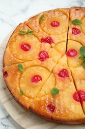 Photo of Delicious cut pineapple pie with cherry and mint on white marble table, closeup