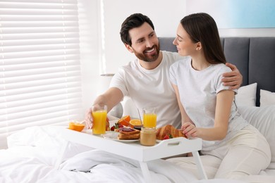 Happy couple having breakfast in bedroom. Space for text