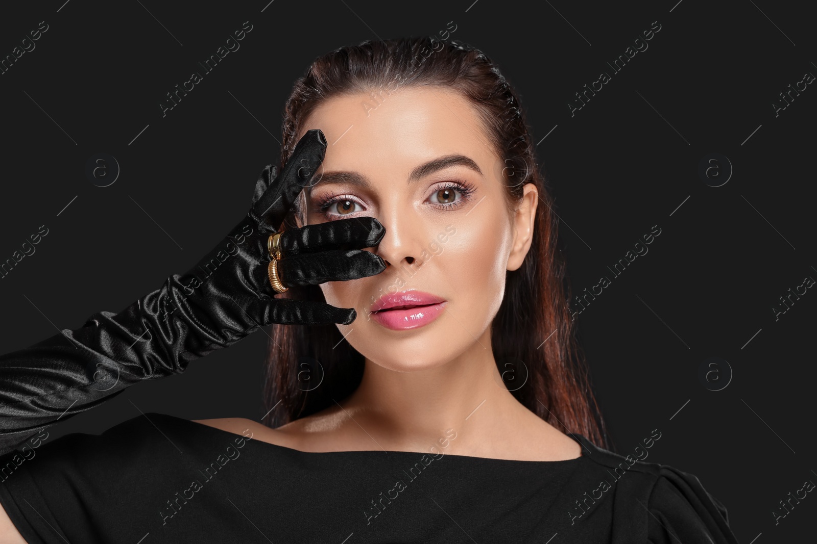 Photo of Portrait of beautiful young woman in elegant evening gloves on black background