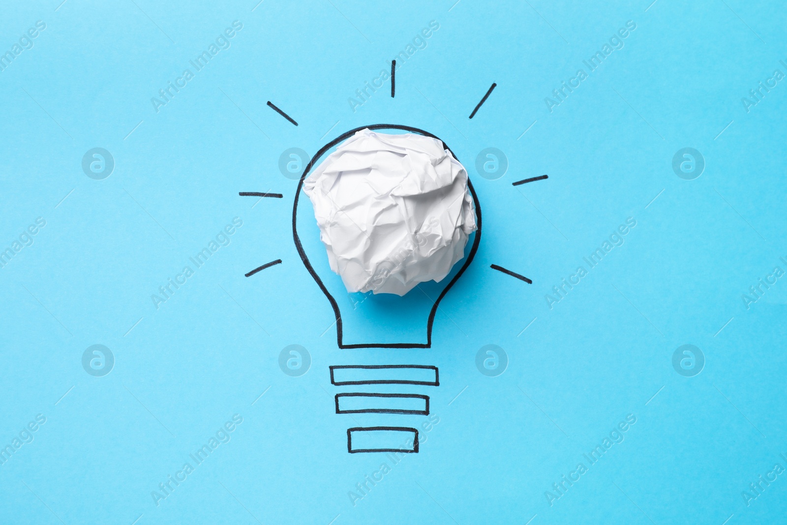 Photo of Idea concept. Light bulb made with crumpled paper and drawing on light blue background, top view