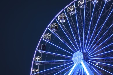 Photo of Big glowing Ferris wheel against dark blue sky at night. Space for text