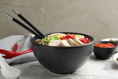 Photo of Delicious ramen in bowl on white marble table, closeup. Noodle soup