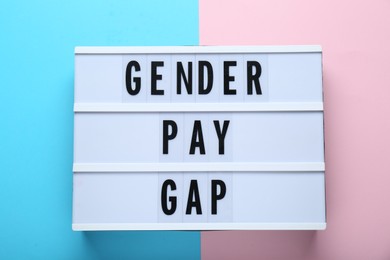 Photo of Lightbox with words Gender Pay Gap on color background, top view