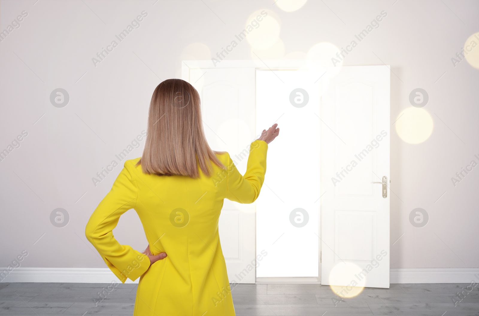 Image of Woman standing in front of open door, back view