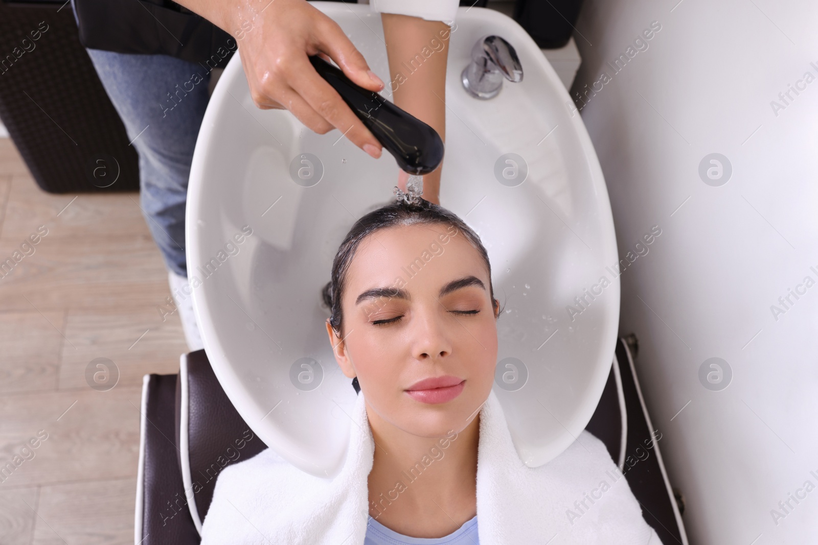 Photo of Professional hairdresser washing woman's hair in beauty salon, above view