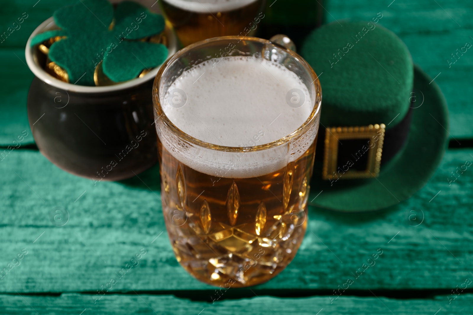 Image of St. Patrick's day. Beer, leprechaun hat, pot of gold and decorative clover leaf on green wooden table